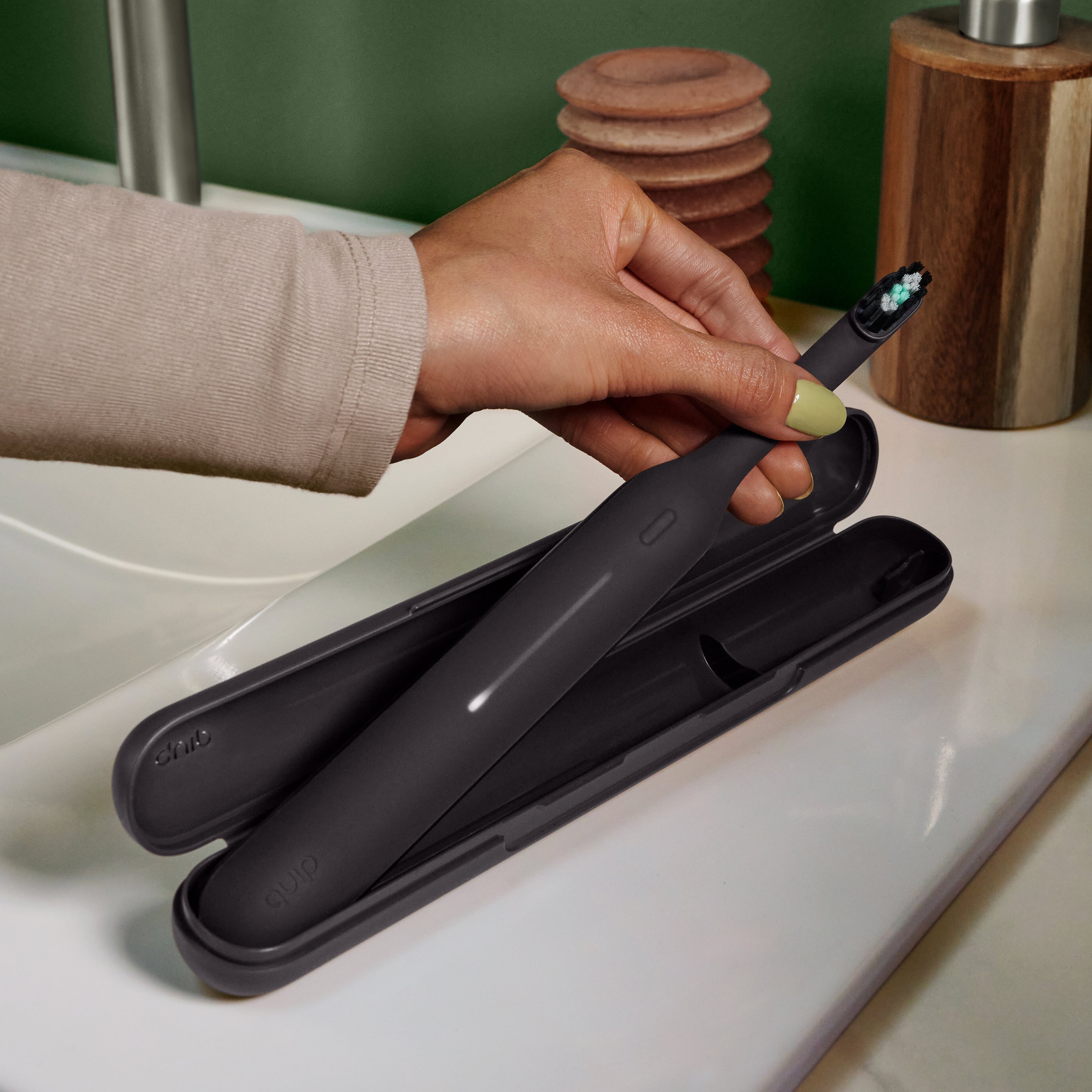 Ultra™ Travel Case holding a sleek black electric toothbrush, shown open on a bathroom counter as a hand lifts the toothbrush from the protective case.