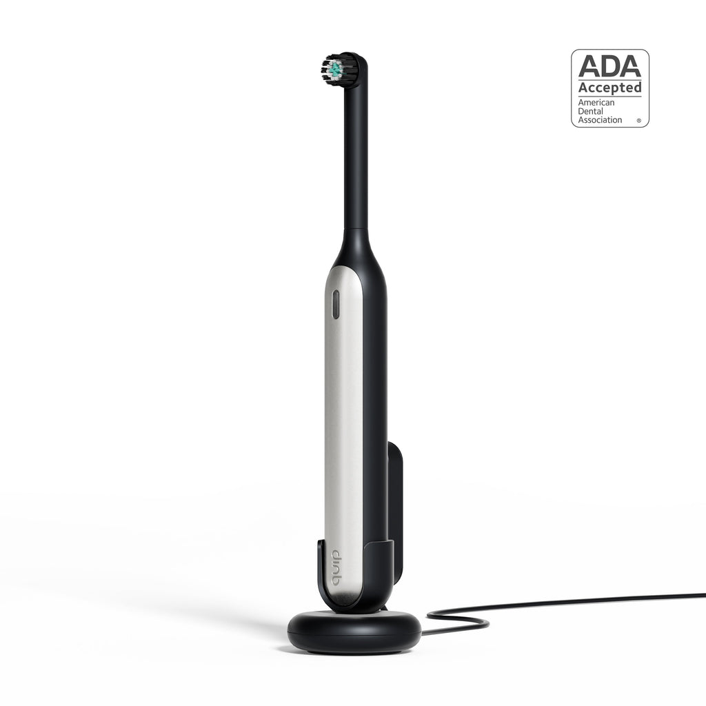 Rev Oscillating Toothbrush in Gray Shadow standing upright on its charging base, featuring a sleek modern design with an ADA Accepted badge displayed beside it.