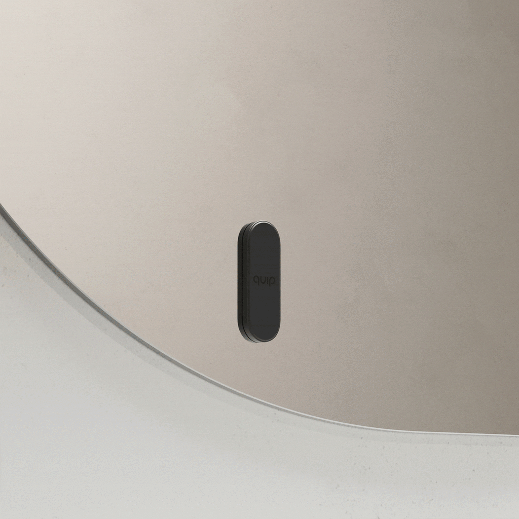 Black quip toothbrush mount attaching to and releasing from a bathroom mirror.