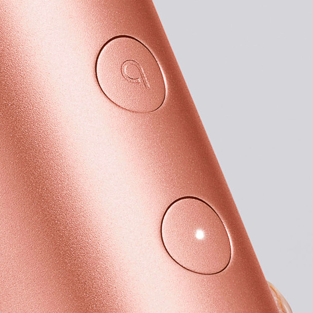 Close-up of a rose gold electronic device with two buttons on a light gray background