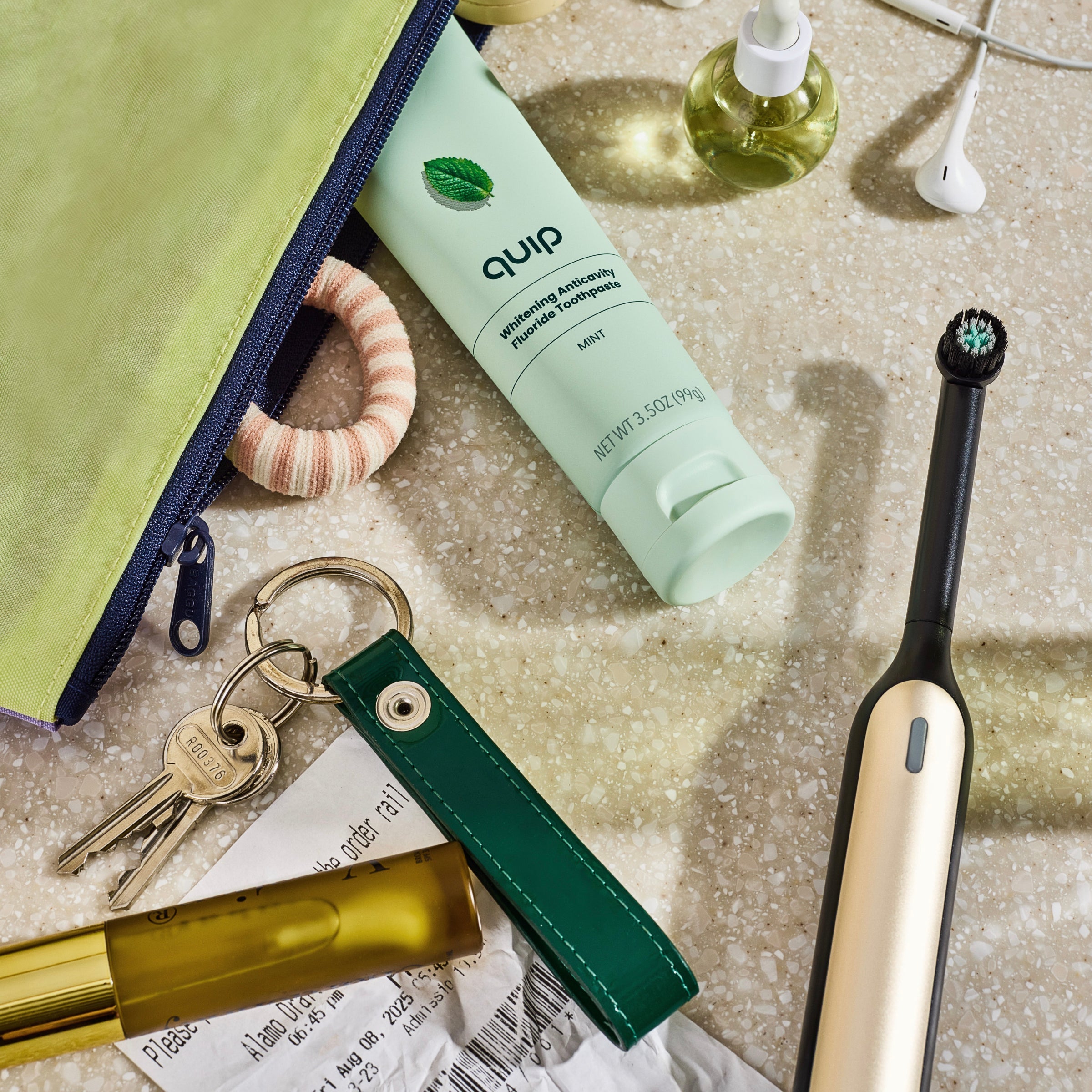Quip electric toothbrush, keychain, and other items on a textured surface