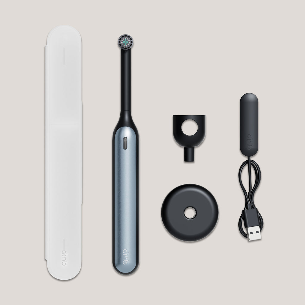 Electric toothbrush set with travel case, brush head, and charging cable on a beige background