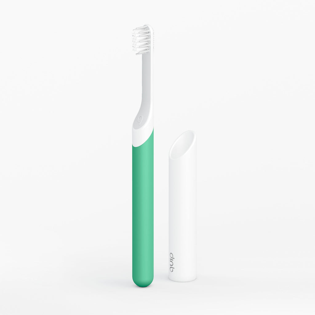 Green and white toothbrush on a light gray background
