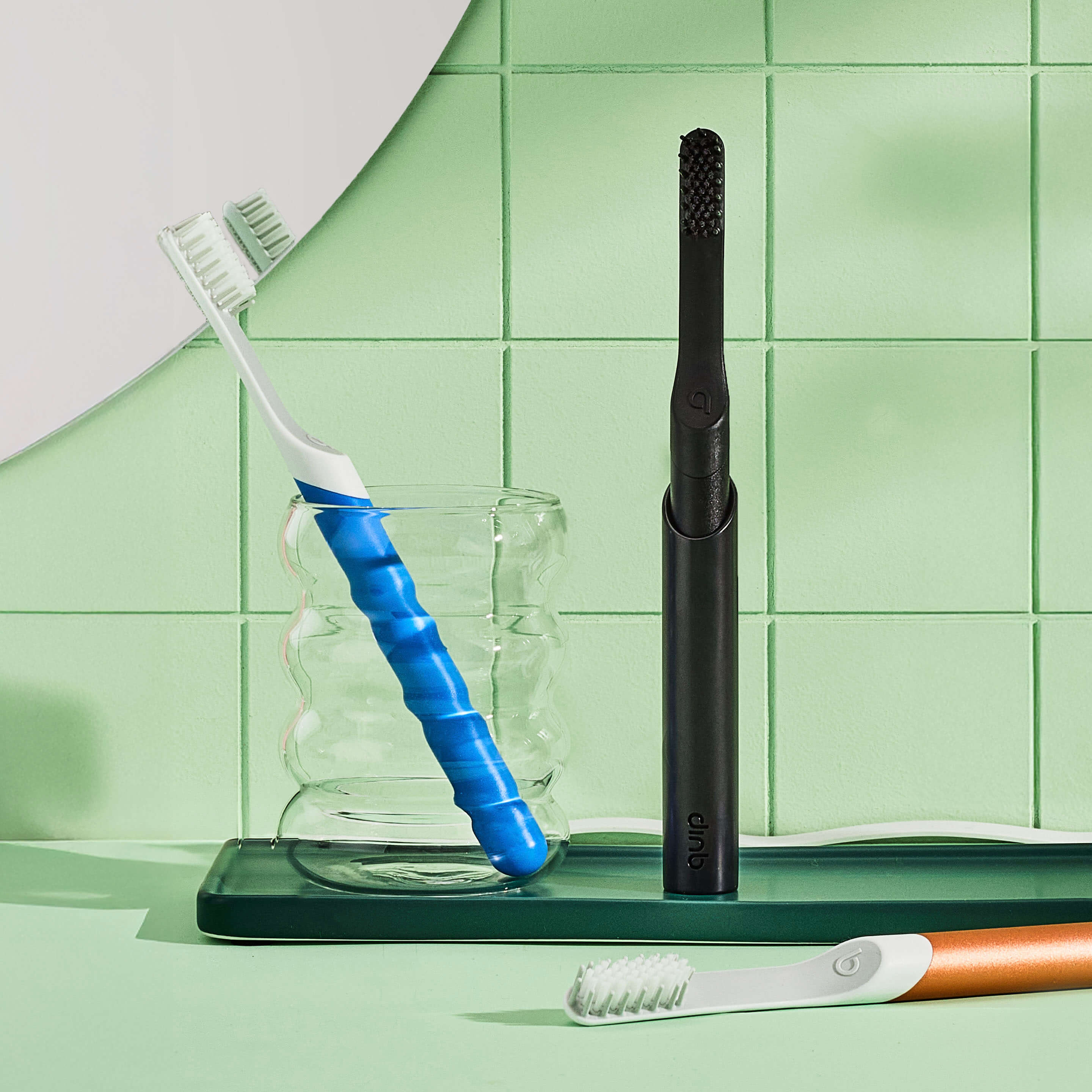 Set of dental tools including a toothbrush, blue tool, and black device on a green tiled background.