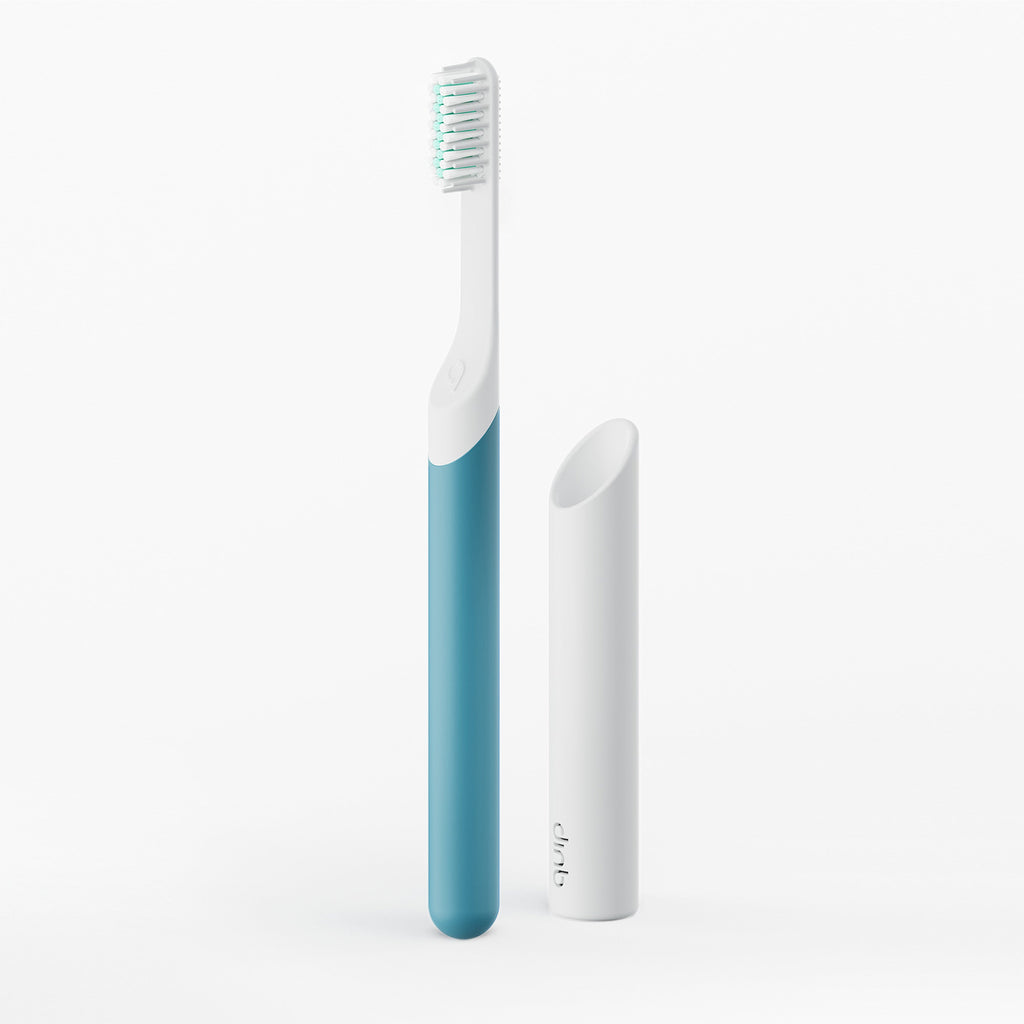 Blue and white toothbrush with a white holder on a light gray background