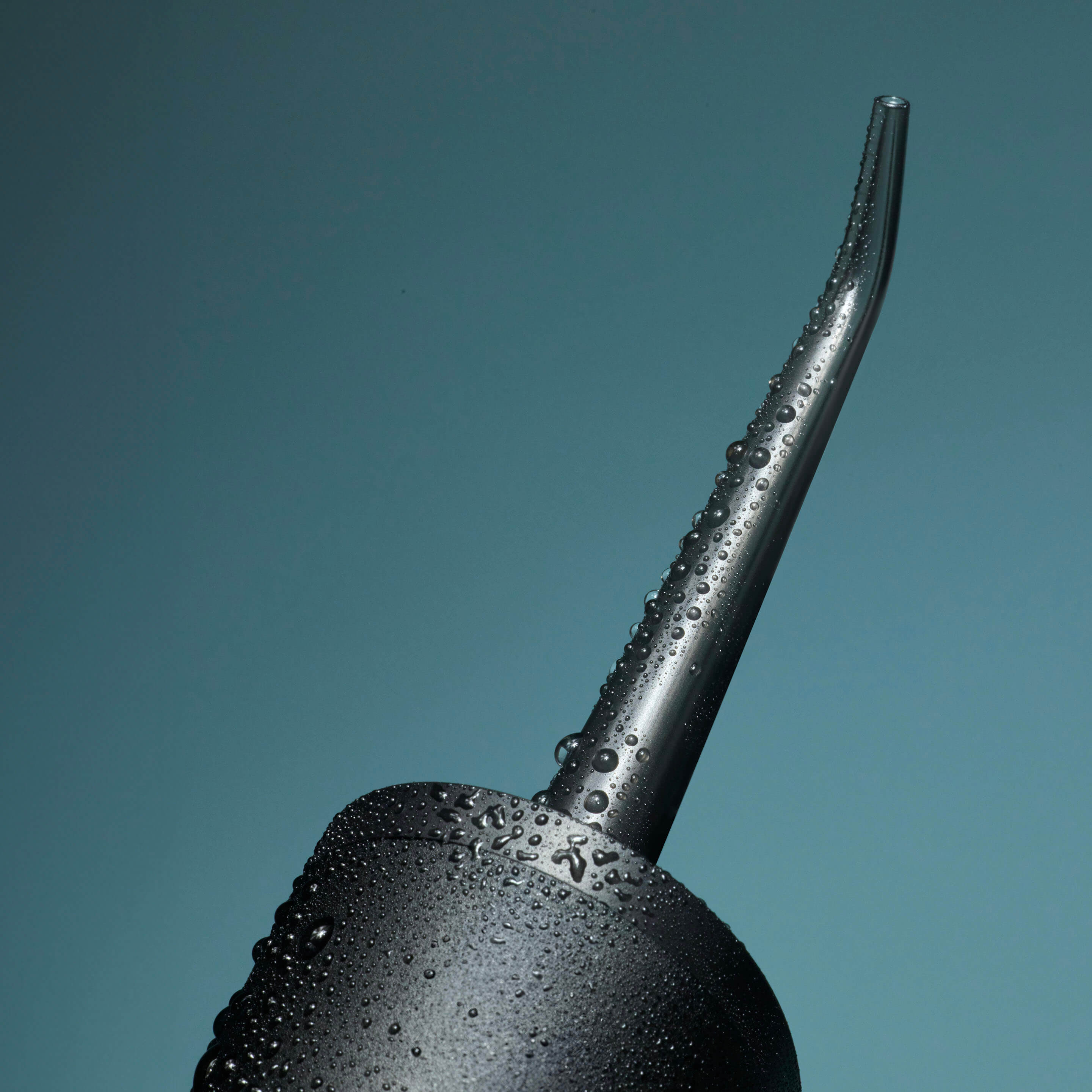 Black argolla with water droplets on a teal background