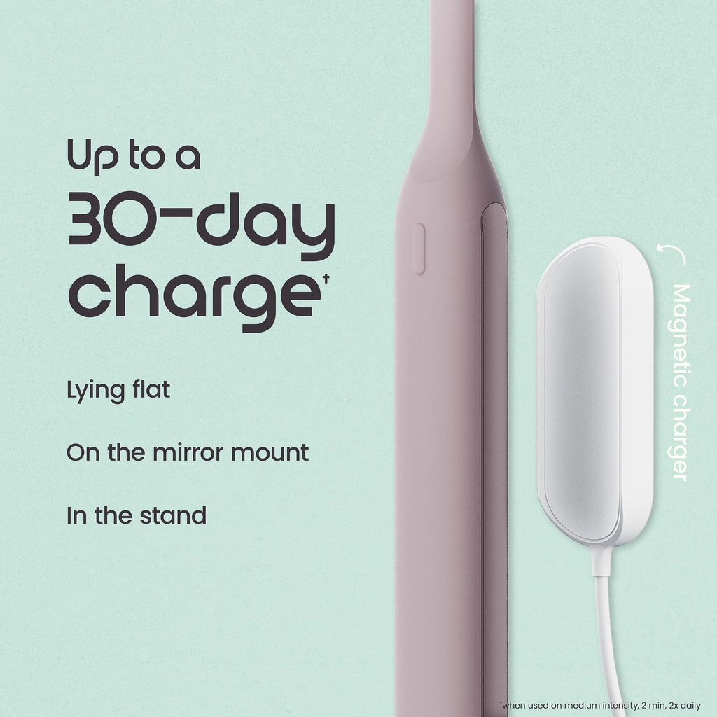 Pink electric toothbrush with charging stand on a light green background
