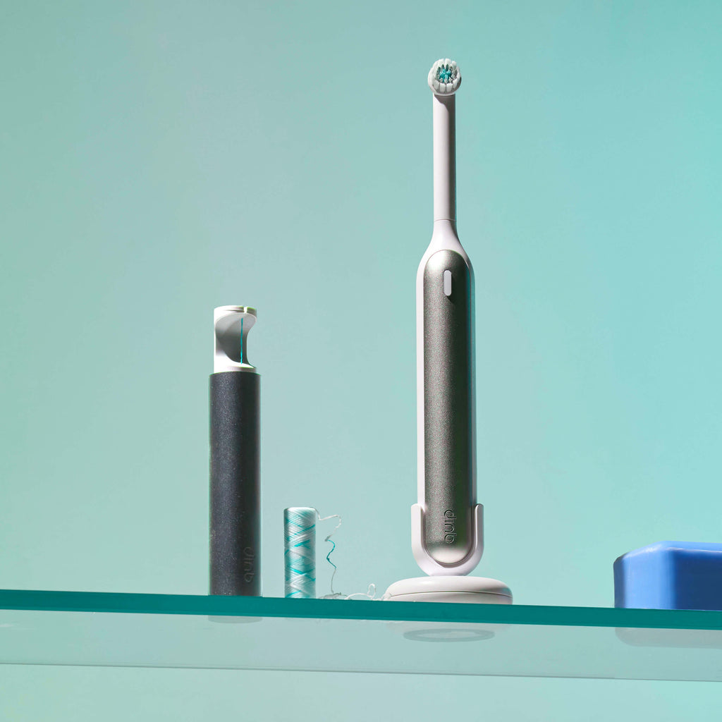 Electric toothbrush on a glass shelf with a teal background